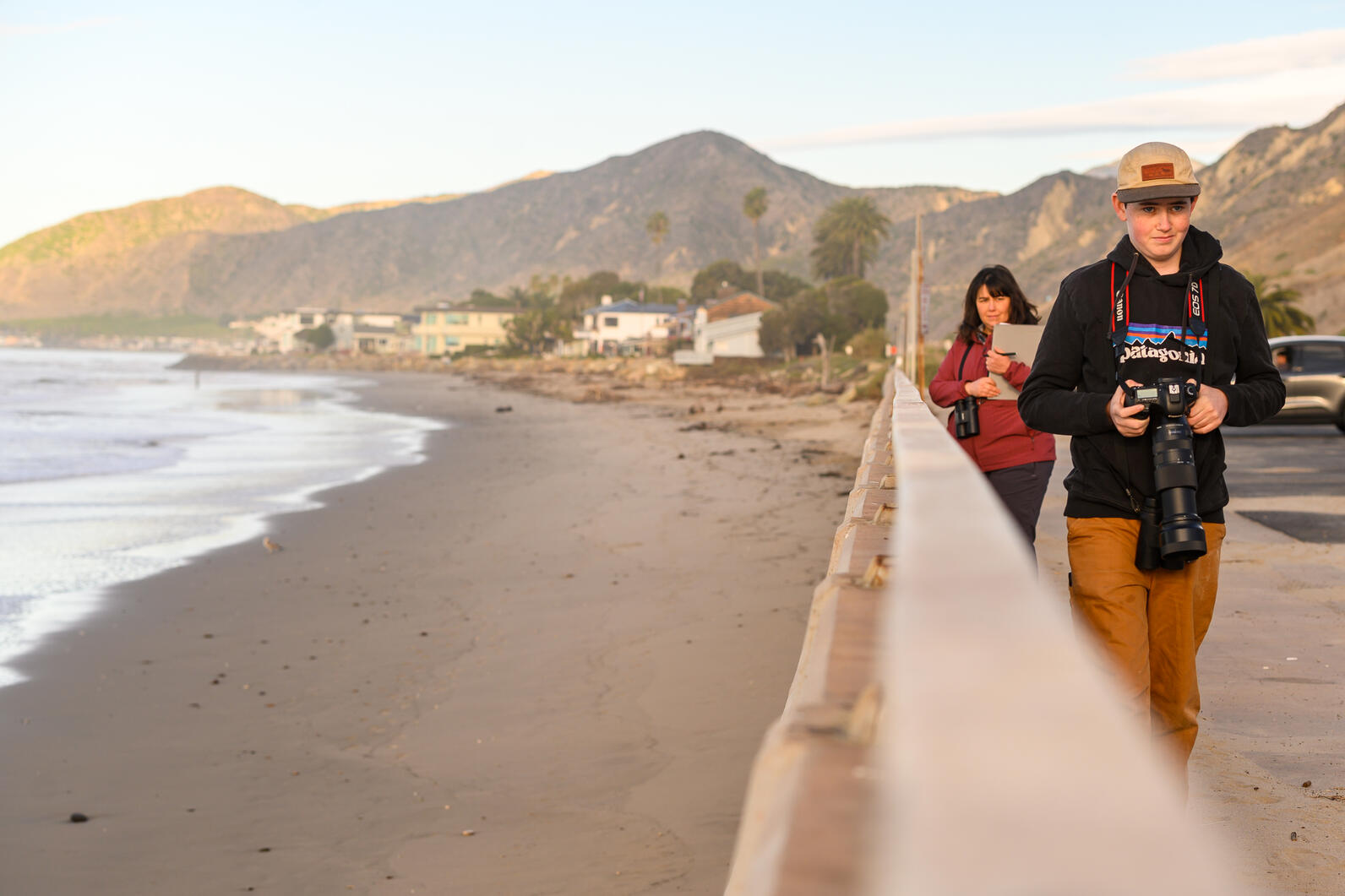 Sara Breshears and Max Breshears counting birds along the Pacific Coast Highway. Sara holds a data sheet while Max holds a camera with a telephoto lens. 